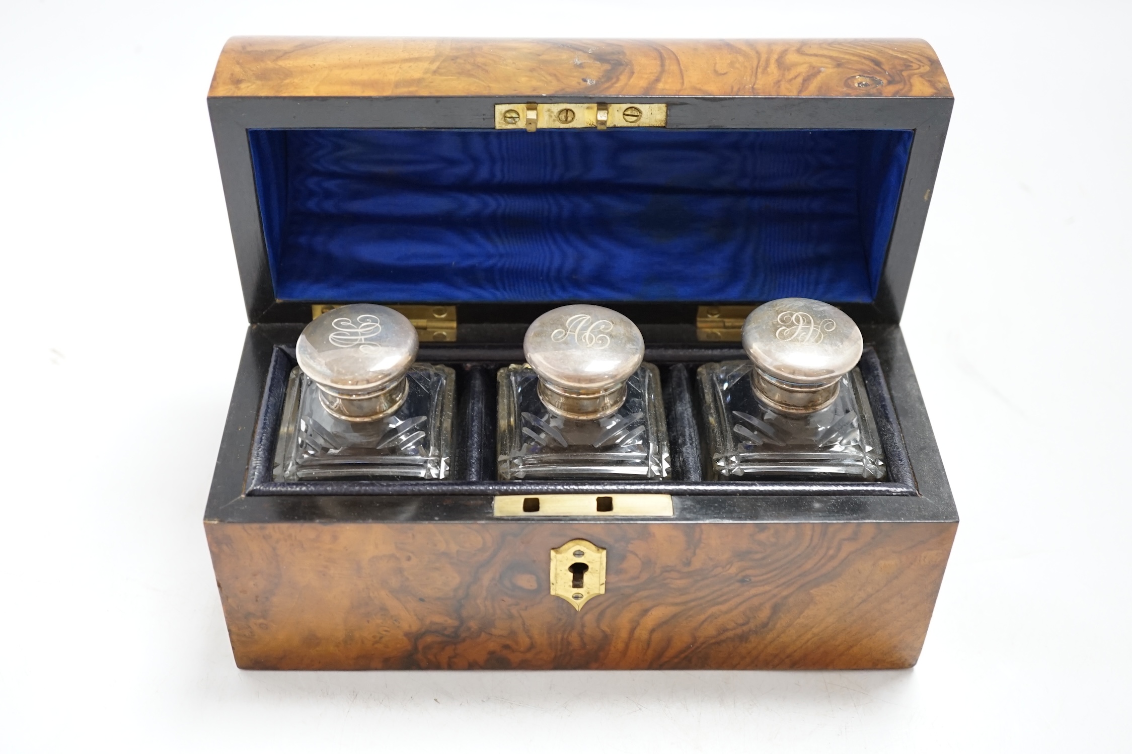 A Victorian walnut dome topped scent bottle case, fitted with three glass bottles with plated mounts, case 20.5cm wide. Condition - metal mount to dome top at the front missing, with minor damage to veneer